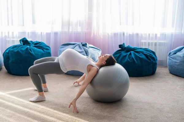 Bella donna europea che fa esercizi di gravidanza. Madre in attesa sta facendo esercizi con una spada fitness. Yoga per donne incinte . — Foto Stock