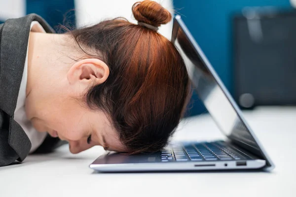 Frustrerad affärskvinna la huvudet på en anteckningsbok vid ett skrivbord. En kvinnlig anställd arbetade övertid och somnade vid en dator på kontoret. Hårt arbetande. — Stockfoto