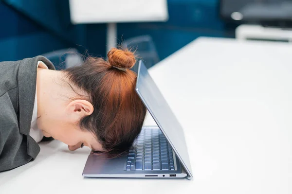 Frustrerad affärskvinna la huvudet på en anteckningsbok vid ett skrivbord. En kvinnlig anställd arbetade övertid och somnade vid en dator på kontoret. Hårt arbetande. — Stockfoto