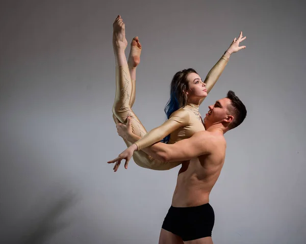 Pareja acrobática realizar el número sobre un fondo blanco. Un dúo de gimnastas ensayando una actuación con apoyo. Un hombre y una mujer muy flexible están bailando. — Foto de Stock