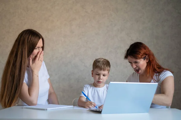Two disgruntled women swear at their son doing homework. Female tutors swear at the boy. A lesbian couple is engaged in home schooling with a child. Distance education in quarantine. — Stock Photo, Image