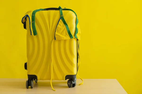 브라질 국기의 갈색 바탕에는 노란색 가방 위에 작은 비키니가 걸려 있다. 여름 방학의 개념이다. 한 여자 가 바다로 여행을 가고 있습니다. — 스톡 사진