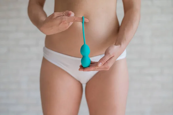 Faceless woman in white panties holding the Kegel trainer for strengthening the intimate muscles of the vagina. Vaginal balls with a displaced center of gravity of a mint color. Sex toy. — Zdjęcie stockowe