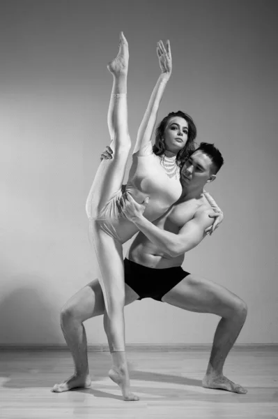 Un uomo e una donna stanno ballando balletto moderno. Coppia acrobatica eseguire il numero su uno sfondo bianco. Un duetto di ginnaste che provano una performance con supporto. Monocromatico foto. — Foto Stock