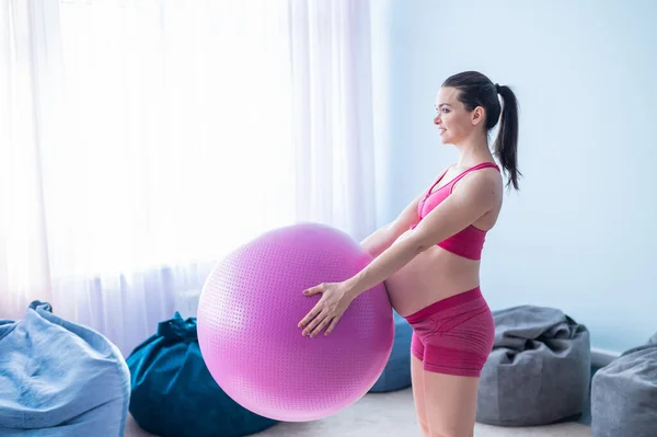 Una mujer embarazada en ropa deportiva está haciendo gimnasia para mujeres embarazadas. La muchacha se ocupa de la aptitud con la pelota para las mamás embarazadas. Último trimestre. —  Fotos de Stock