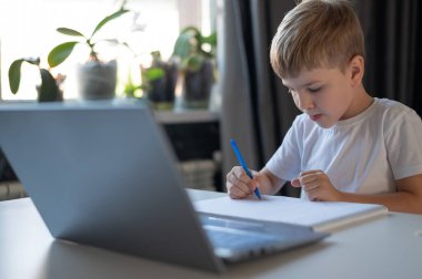 Çocuk dizüstü bilgisayardaki web kamerasından öğretmenle iletişim kuruyor. İnternetten ders. Karantinada uzaktan eğitim. Çalışkan bir öğrenci Coronavirus salgınında evde çalışıyor..