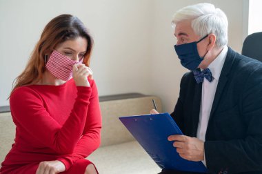 Erkek psikoterapist, tıbbi maskeli bir kadın müşteriye tavsiye eder. Koronavirüs salgını sırasında manevi destek. Depresyondaki kadın psikoloğa gidiyor. Hastalık ve panik atak tedavisi