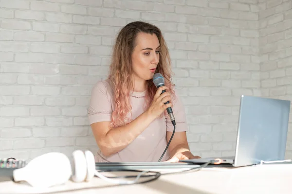 Uma mulher registra uma lição vocal usando um laptop e acompanhando em um teclado enquanto está em casa. O professor canta uma música no microfone e toca piano eletrônico. Um blogueiro está gravando um vídeo. — Fotografia de Stock