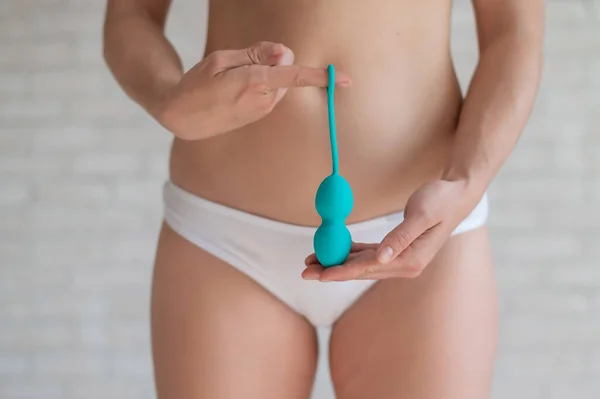 Faceless woman in white panties holding the Kegel trainer for strengthening the intimate muscles of the vagina. Vaginal balls with a displaced center of gravity of a mint color. Sex toy. — Stock Photo, Image