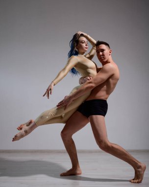 Akrobatik çift beyaz bir arkaplanda şarkı söylüyor. Bir jimnastikçi düeti bir performansı destekle prova ediyor. Bir adam ve çok esnek bir kadın dans ediyorlar..