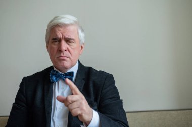 Takım elbiseli, papyonlu, beyaz saçlı, ciddi bir adamın portresi. Zarif giyimli, temiz tıraşlı bir son sınıf öğrencisi kameraya özgüvenle bakar ve parmağını gösterir. Hareketlendirme.