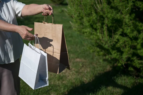 Primeros planos de una anciana con bolsas de papel ecológicas en el parque. La abuela tiene bolsas de papel afuera. Foto recortada . —  Fotos de Stock