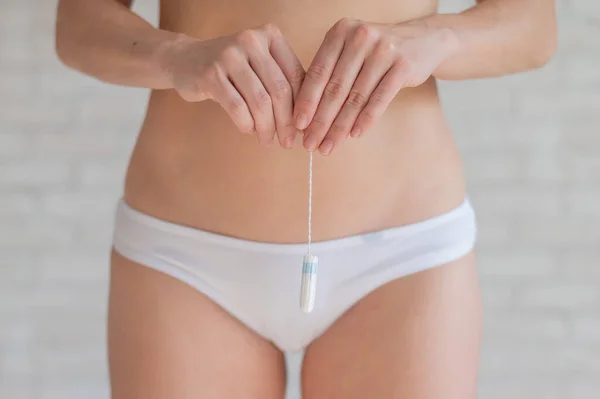 Kobieta bez twarzy w białych majtkach trzyma tampon podczas regularnego cyklu miesiączkowego. Kobiecy produkt higieny absorpcyjnej. Komfort podczas miesiączki. — Zdjęcie stockowe