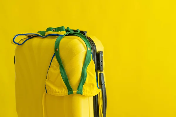 女性比基尼在一个黄色背景的手提箱上。准备在海上度过暑假.工作室里泳衣和泳袋的构成. — 图库照片