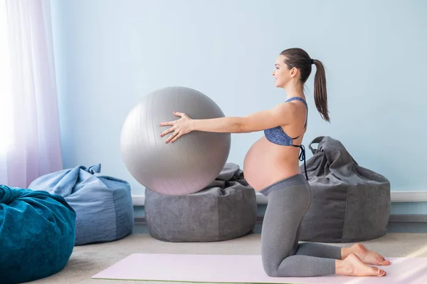Gravid kaukasiska kvinna på fitness med en boll. Yoga för blivande mödrar. Flicka i klassrummet som förberedelse för förlossning. Pilates under den sista trimestern. — Stockfoto