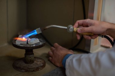 Bir diş teknisyeni kısmi takma diş yapar. Manüel gaz ocağı kullanılarak sahte çene ya da diş köprüsü üretimi. Yakın plan..