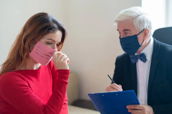 Male psychotherapist advises a female client in a mask. Moral support during the coronavirus epidemic. Depressed woman on a session to a psychologist. Treatment of hypochondria and panic attacks