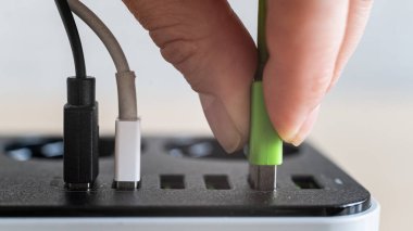 Cihazlar için modern çoklu port usb şarj cihazı. Çok renkli kabloları elektrik prizine takan bir kadının yakın çekimi. Makro.