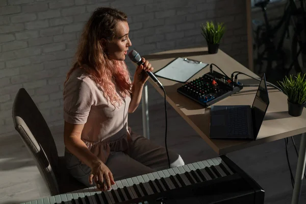 Eine Bloggerin singt und spielt live elektronisches Klavier. Porträt eines Mädchens, das einen Song mit einer Webkamera aufnimmt und auf einem Synthesizer komponiert. Online-Musikunterricht. Fernstudium in Quarantäne. — Stockfoto