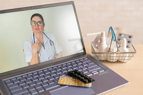 Відеоконференція з лікарем на ноутбуці та планшеті в маленькому кошику для покупок. Інтернет-аптека. Фармацевт на екрані комп'ютера . — стокове фото