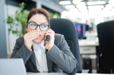 Ofisinde bir kadın oturuyor ve telefonda dedikodularını yapıyor. Şirket ahlakı. Takım elbiseli kadın çalışan, iş yerindeki akıllı telefondan sırlarını anlatır..
