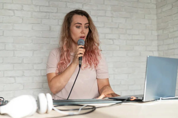 Egy nő felvesz egy hangórát egy laptoppal, és kíséri a billentyűzeten, miközben otthon van. A tanár énekel egy dalt a mikrofonba, és játszik az elektronikus zongorán. Egy blogger felvesz egy videót.. — Stock Fotó