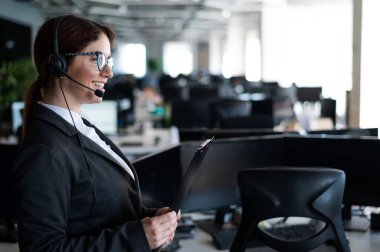 Kadın yardım görevlisi elinde bir klasörle ayakta duruyor. Kulaklıklı bir ofis yöneticisi müşteri aramalarına cevap verir. Gözlüklü, güler yüzlü bir kadın sekreter olarak çalışıyor. Çalışan Çağrı Merkezi.