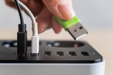 Cihazlar için modern çoklu port usb şarj cihazı. Çok renkli kabloları elektrik prizine takan bir kadının yakın çekimi. Makro.