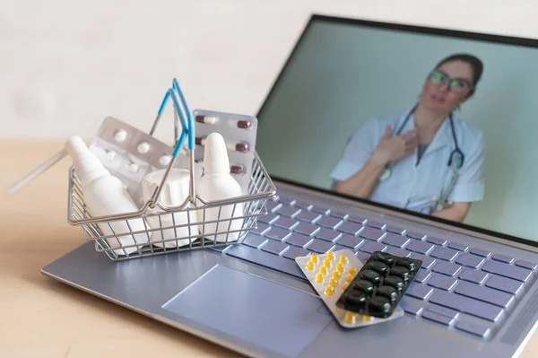 Videokonferencia egy orvossal egy laptopon és táblagépen egy kis bevásárlókosárban. Online gyógyszertár. Gyógyszerész számítógép képernyőn. — Stock Fotó