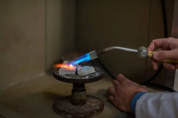 Un técnico dental hace dentaduras parciales. La producción de una mandíbula falsa o puentes dentales utilizando un quemador de gas manual. Primer plano . — Foto de Stock