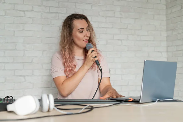 Eine Frau nimmt eine Gesangsstunde mit einem Laptop auf und begleitet sie zu Hause auf einem Keyboard. Die Lehrerin singt ein Lied ins Mikrofon und spielt elektronisches Klavier. Ein Blogger nimmt ein Video auf. — Stockfoto