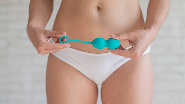 Faceless woman in white panties holding the Kegel trainer for strengthening the intimate muscles of the vagina. Vaginal balls with a displaced center of gravity of a mint color.Female health concept. — Zdjęcie stockowe