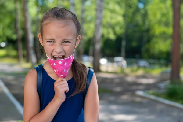 Portret van een gelukkig blank meisje dat gezichtsmasker buiten afdoet. Uiteindelijk zal de quarantaine eindigen. Overwinning op het coronavirus. — Stockfoto