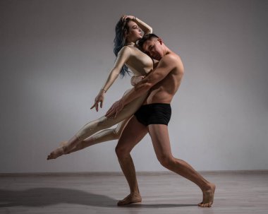 Akrobatik çift beyaz bir arkaplanda şarkı söylüyor. Bir jimnastikçi düeti bir performansı destekle prova ediyor. Bir adam ve çok esnek bir kadın dans ediyorlar..