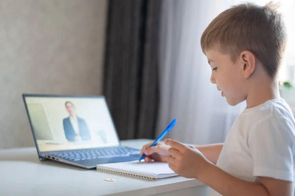 El niño se comunica con una maestra en una webcam portátil. Lección en línea. Educación a distancia en cuarentena. Un escolar está estudiando en casa en la epidemia de coronavirus . — Foto de Stock