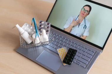 Bilgisayarda bir doktorla video konferansı ve küçük bir alışveriş sepetinde tablet. İnternetteki eczane. Bilgisayar ekranındaki eczacı..