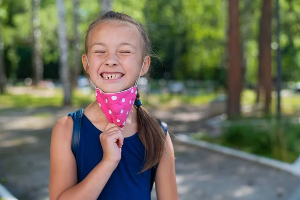 Portret van een gelukkig blank meisje dat gezichtsmasker buiten afdoet. Uiteindelijk zal de quarantaine eindigen. Overwinning op het coronavirus. — Stockfoto