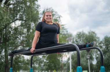 Güzel, güler yüzlü, aşırı kilolu genç bir kadın, açık havada düz olmayan barlarda kırışmak için geriniyor. Spor sahasında spor yapan şişman bir jimnastikçi kız. Sıcak bir yaz gününde dışarıda spor..