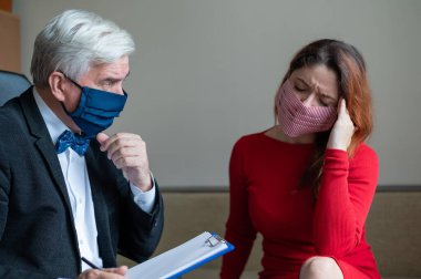 Erkek psikoterapist, tıbbi maskeli bir kadın müşteriye tavsiye eder. Salgın sırasında manevi destek. Depresyondaki kadın psikoloğa gidiyor. Koronavirüste panik atak tedavisi.