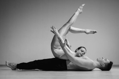 Ağır sirk pozu. Genç bir adam esnek bir kadını tutuyor. Beyaz arka planda poz veren iki akrobat ya da balerin. Bir çift jimnastikçi sanat icra ediyor..