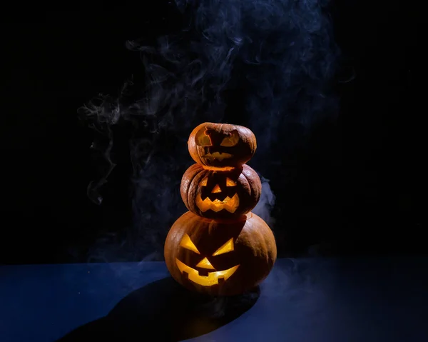 A spooky pyramid of jack-o-lantern in the dark. Glowing scary smirk carved in a pumpkin. Traditional halloween decorations. Horizontal greeting card or banner. — Stock Photo, Image