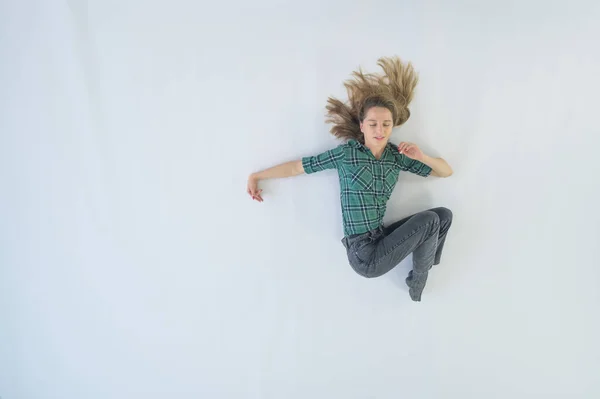 Вид зверху на дівчину, що лежить на білому тлі. Жінка в плетеній сорочці і джинсах . — стокове фото