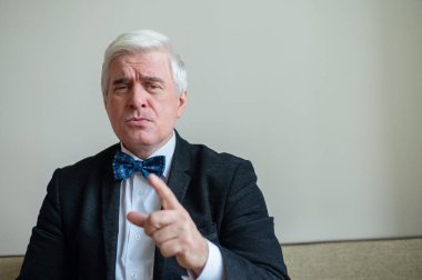 Takım elbiseli, papyonlu, beyaz saçlı, ciddi bir adamın portresi. Zarif giyimli, temiz tıraşlı bir son sınıf öğrencisi kameraya özgüvenle bakar ve parmağını gösterir. Hareketlendirme.