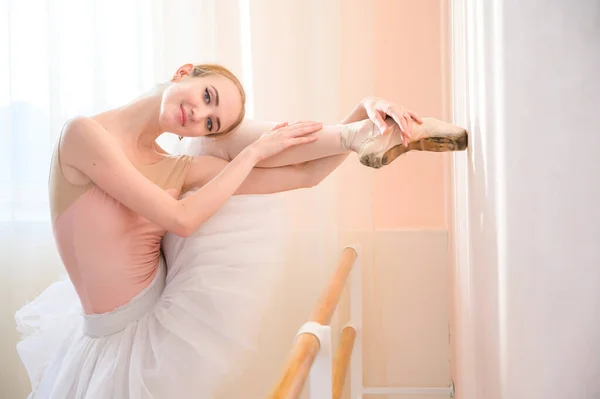Όμορφη χαριτωμένη μπαλαρίνα εξασκείται στην αίθουσα με φόντο ένα παράθυρο. Λεπτή γυναίκα σε tutu και pointe παπούτσια σε ένα μάθημα χορού. — Φωτογραφία Αρχείου