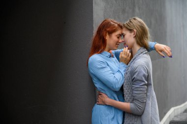 Tutkulu bir lezbiyen çift. Gri bir duvarın karşısında şefkatle sarılan iki güzel genç kadın. LGBT komünü. Kızlar randevuda..