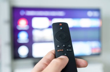 Bulanık bir televizyonun arka planında netflix logosu olan bir adam elinde uzaktan kumanda tutuyor. Film ve TV şovlarına sınırsız erişimi olan bir portal.