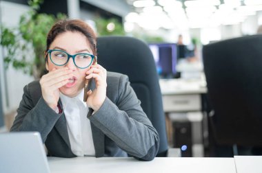 Ofisinde bir kadın oturuyor ve telefonda dedikodularını yapıyor. Şirket ahlakı. Takım elbiseli kadın çalışan, iş yerindeki akıllı telefondan sırlarını anlatır..