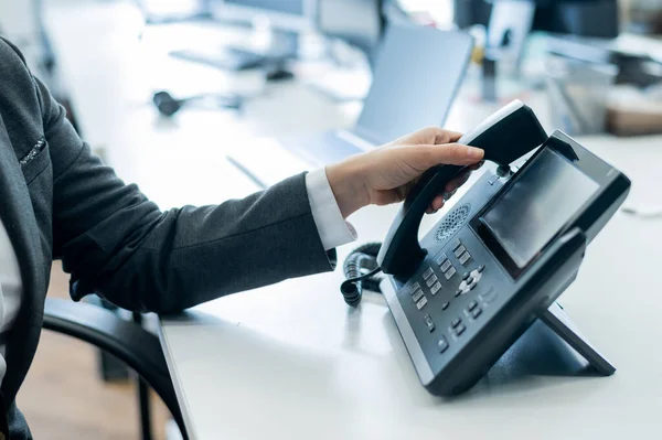 Ofisteki ev telefonunda kadın eli var. Takım elbiseli meçhul kadın müşteri aramalarına cevap veren resepsiyonist olarak çalışıyor.. — Stok fotoğraf