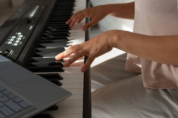 Closeup of female hands on an electronic piano. A laptop on a keyboard instrument. Online lesson. Distance learning music. — Stock Photo, Image