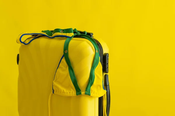 Женское бикини на чемодане на желтом фоне. Отправьтесь на летний отдых на море. Состав купальника и сумки в студии. — стоковое фото